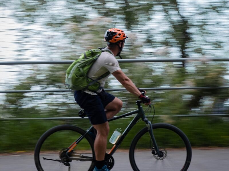 a man riding a bike down a street next to a lake